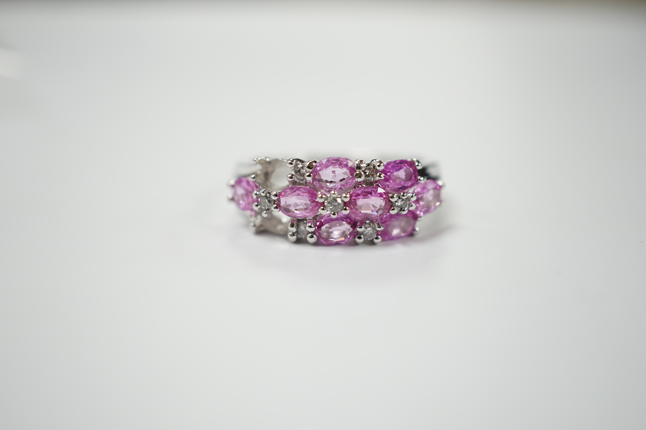 A modern 14k white metal, pink sapphire and diamond cluster set half hoop ring (two sapphires loose), size O, gross weight 4.7 grams.